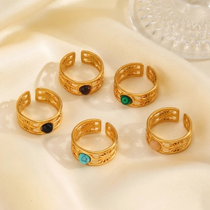 Golden sunburst open rings with colorful gemstones on a beige silk background