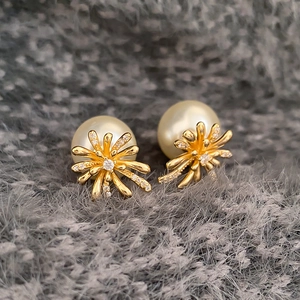 Macro shot of gold floral earrings with sparkling cubic zirconia and elegant white pearls