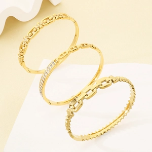 Detailed close-up of three gold chain bracelets with diamond accents on stone props