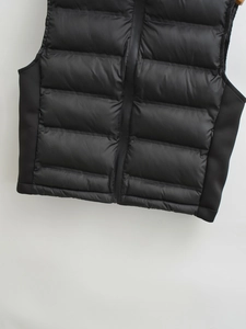 Detail of black quilted vest featuring horizontal stitching and waterproof zipper closure