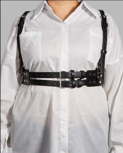 Detail of adjustable black leather harness belt with metal buckles over white shirt