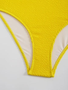 Vue détaillée du tissu gaufré jaune du maillot de bain avec doublure blanche et texture
