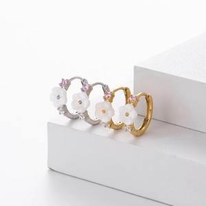 Detail of S925 silver hoop earrings with white flower charms and pink cubic zirconia