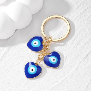Blue evil eye heart keychain with gold alloy tassels on a white textured background