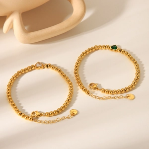Detail of 18K gold stainless steel bead bracelets with green and clear heart charms