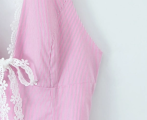 Close-up of pink striped dress featuring white floral lace trim and V-neckline details