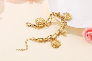 Detailed view of golden double-layer bracelet with sun pendants and lobster clasp closure