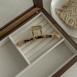Detailed view of large gold metal leopard print hair claw clip in a velvet jewelry box