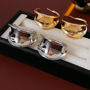 Macro detail of polished gold and silver C-shaped chunky earrings in a jewelry box