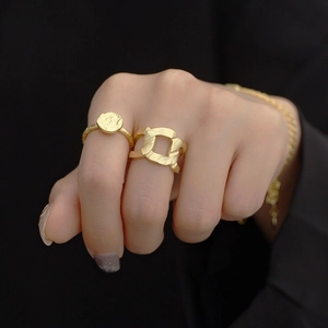 Detail of gold S925 silver rings with foil texture and chain link design on hand