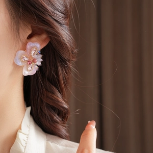 Détail d'une boucle d'oreille fleur en résine avec perles et strass roses portée par un mannequin
