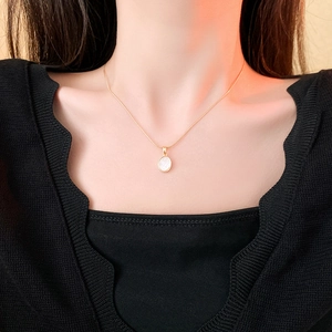 Gros plan détaillé d'un collier en acier titane doré avec un pendentif ovale en nacre