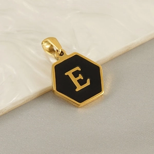 Detail of a gold hexagon pendant with black enamel inlay and gold letter E engraving
