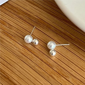 Detailed close-up of 925 sterling silver pearl stud earrings on a wooden background