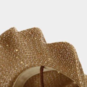 Macro view of woven straw sun hat with sparkling metallic threads and wavy edge