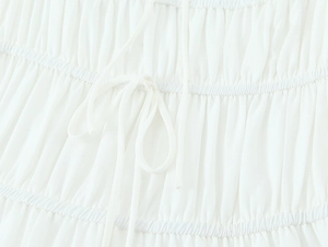 Détails de la texture plissée blanche et du cordon de serrage sur cette robe d'été chic