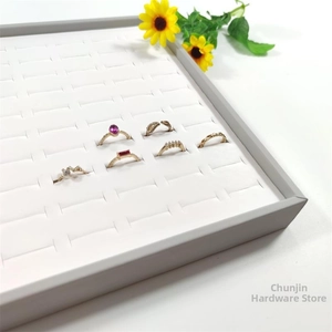Close-up of a 100-slot gray jewelry display tray holding various gold and gemstone rings
