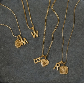 Detail view of 18K gold plated bamboo alphabet pendants and charms on steel necklaces