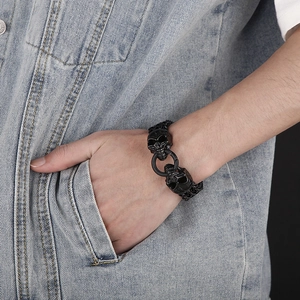 Close-up of mens black stainless steel bracelet with dual skull head clasp on denim