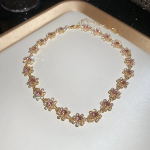 Macro detail of gold flower necklace with pink crystal centers and sparkling diamonds