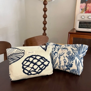 Detail of fabric cosmetic bags with blue floral prints on a rustic wooden table