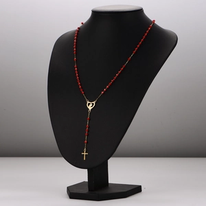 Stainless steel rosary necklace with red beads, cross pendant and heart medal on a mannequin