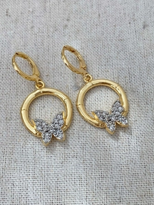 Macro shot of gold butterfly earrings with micro-inlaid white zircons on fabric