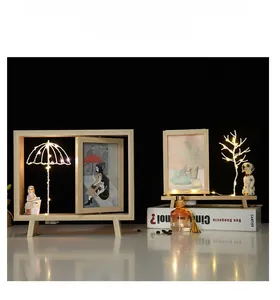 Détail du cadre photo rotatif en bois avec guirlandes LED chaudes et figurines miniatures