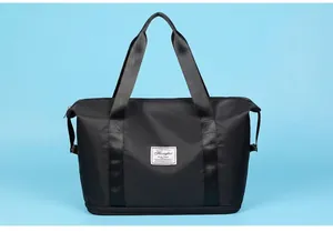 Detailed view of black waterproof travel bag with reinforced straps and logo on blue background