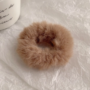 Close-up detail of soft fluffy brown plush hair scrunchie with thick velvet texture
