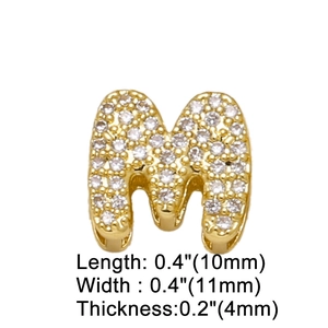 Detail view of a gold-plated letter M charm with clear zircon inlay and size parameters