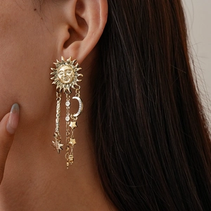 Close-up of golden sun, moon and star tassel earrings on model with retro style