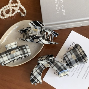 Classic black and white checkered hair claw set with gold-tone branding on wood surface