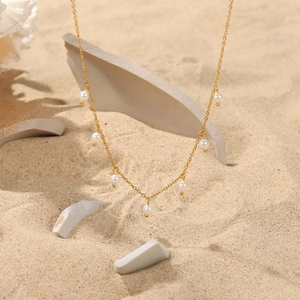 Elegant 18K gold stainless steel necklace with seven white pearl pendants on sand