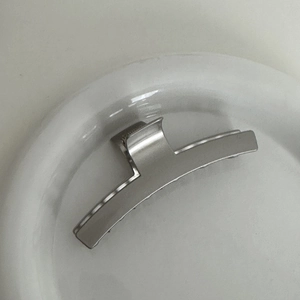 Detailed top view of a premium silver metal bow hair claw clip on a white ceramic plate