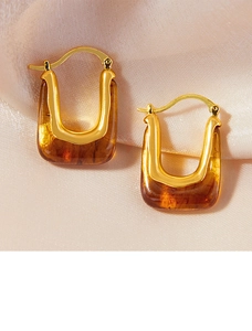 Close-up of vintage U-shaped earrings with amber resin and gold metal on silk
