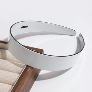 Detail of white wide headband with black trim on a wooden jewelry display tray