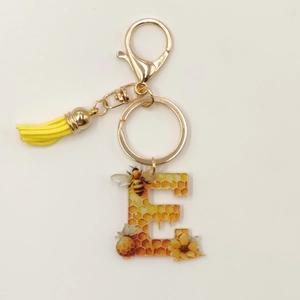 Close-up of letter E honey bee keychain with yellow tassel and golden clasp hardware