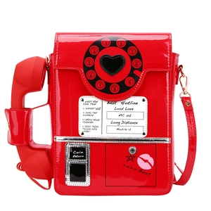 Macro view of red retro telephone handbag with glossy finish and dial detailing