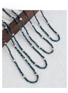 Detail of handmade phoenix lapis lazuli and pink freshwater pearl beaded necklaces on wood