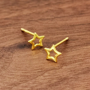 Minimalist S925 sterling silver hollow star stud earrings in gold on dark wood surface