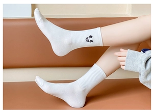 Close-up of white cotton mid-calf socks with cute black embroidered expression patterns