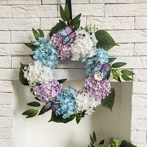 Detail of autumn hydrangea wreath with colorful butterflies on a white brick fireplace