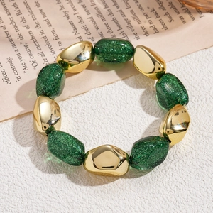 Close-up of green glitter resin beads and gold irregular charms on elastic bracelet