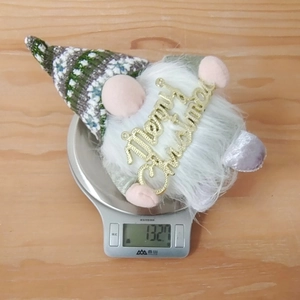 Detailansicht der 132,7g schweren Weihnachtswichtel-Puppe auf einer digitalen Waage