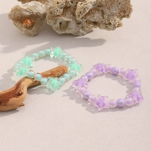 Star-shaped beaded bracelets in jelly mint green and lavender on a coral background