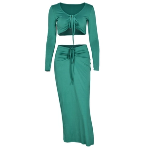Detail of green two-piece knit set featuring drawstring ruched long sleeve top and skirt