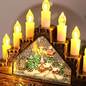 Close-up of bronze Christmas candle bridge with warm LED lights and festive snow scene