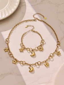 Détail de parure collier et bracelet dorés en acier inoxydable avec lunes et étoiles
