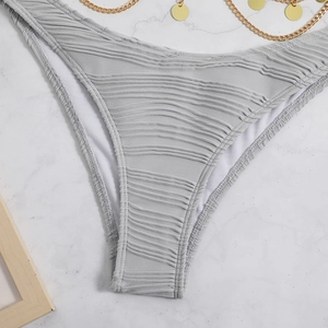 Detail view of light gray bikini bottoms with textured pleated fabric and gold chain accents
